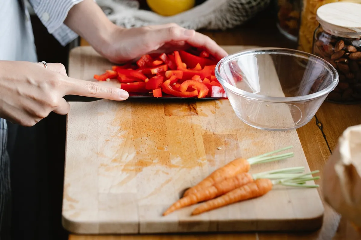 Commis de cuisine découpant des légumes sur planche