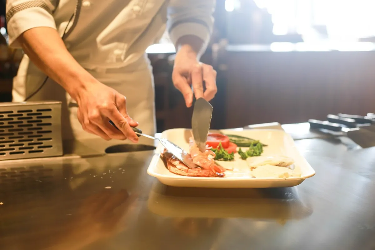 Équipier de restauration dressant des assiettes en cuisine
