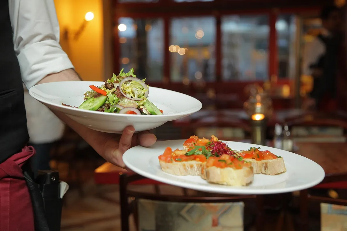 Serveur apportant des plats en salle de restaurant