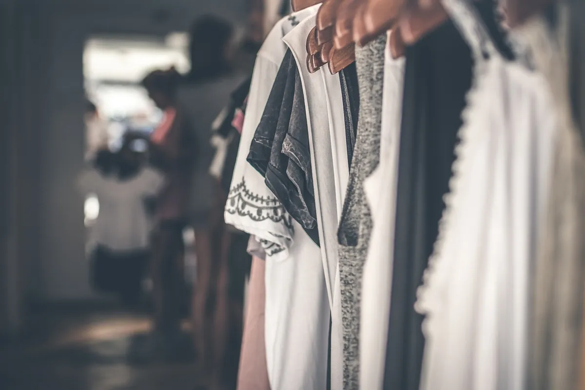 Vendeur en magasin parmi des vêtements sur cintres